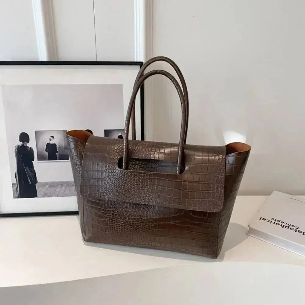 Dark brown crocodile pattern large tote handbag for women on white table