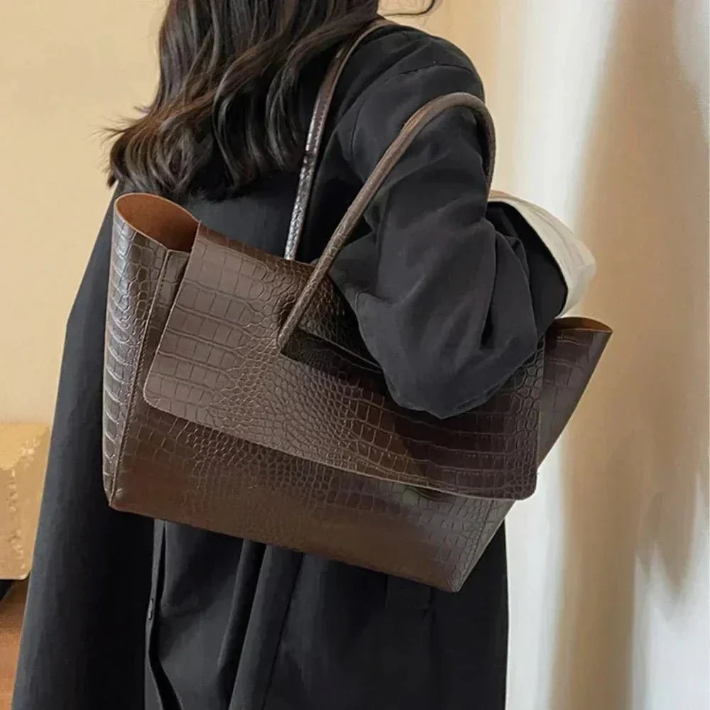 Woman carrying large dark brown crocodile pattern tote handbag on shoulder
