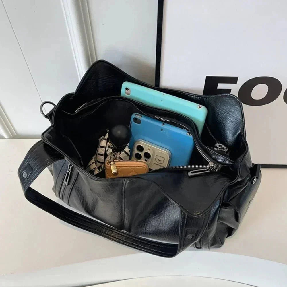 Spacious black shoulder bag for women with multiple compartments, holding tablet, phone, and accessories