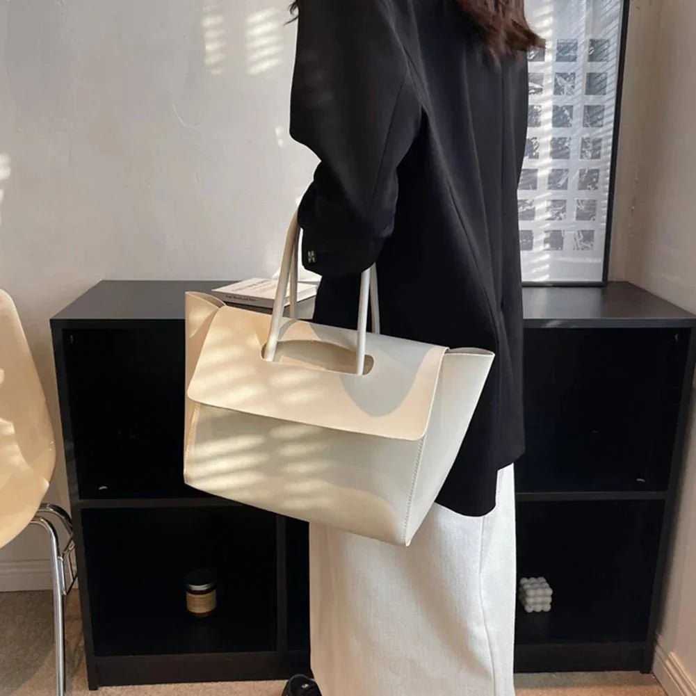 Woman holding large white vegan leather tote bag with top handles in modern room