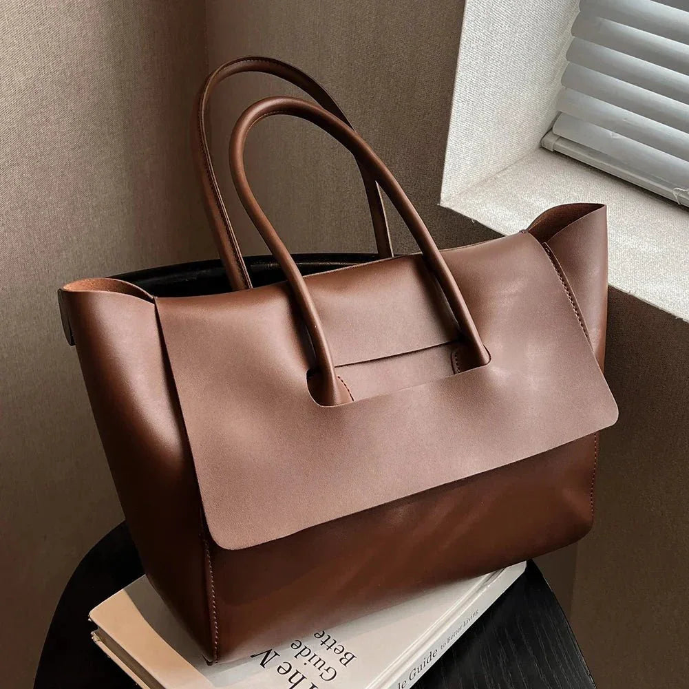 Dark brown vegan leather large shoulder tote purse with double handles on a side table.